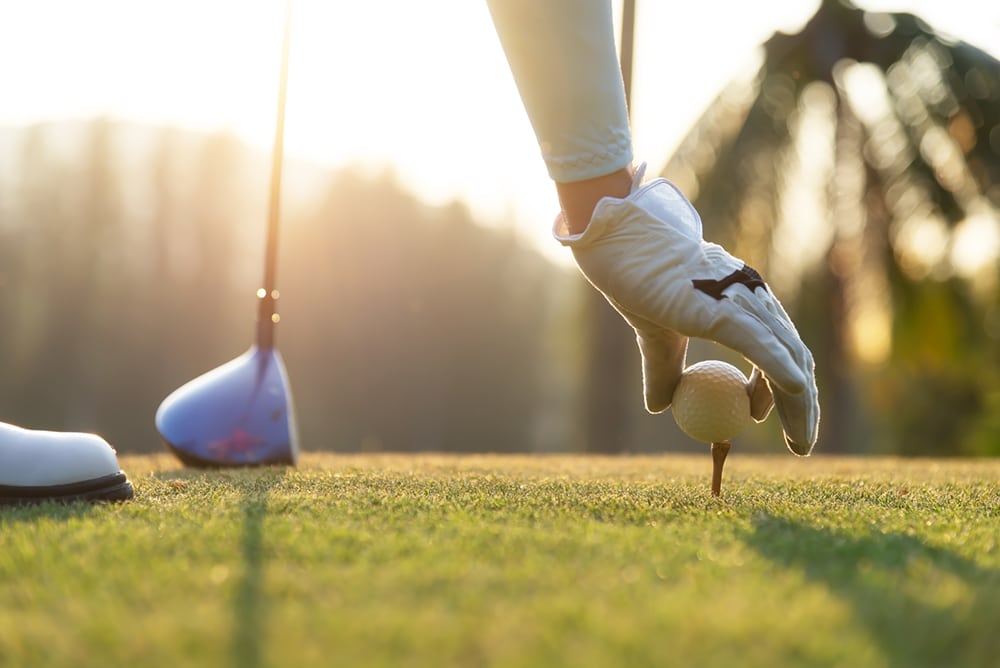A golfer places a golf ball on a tee.